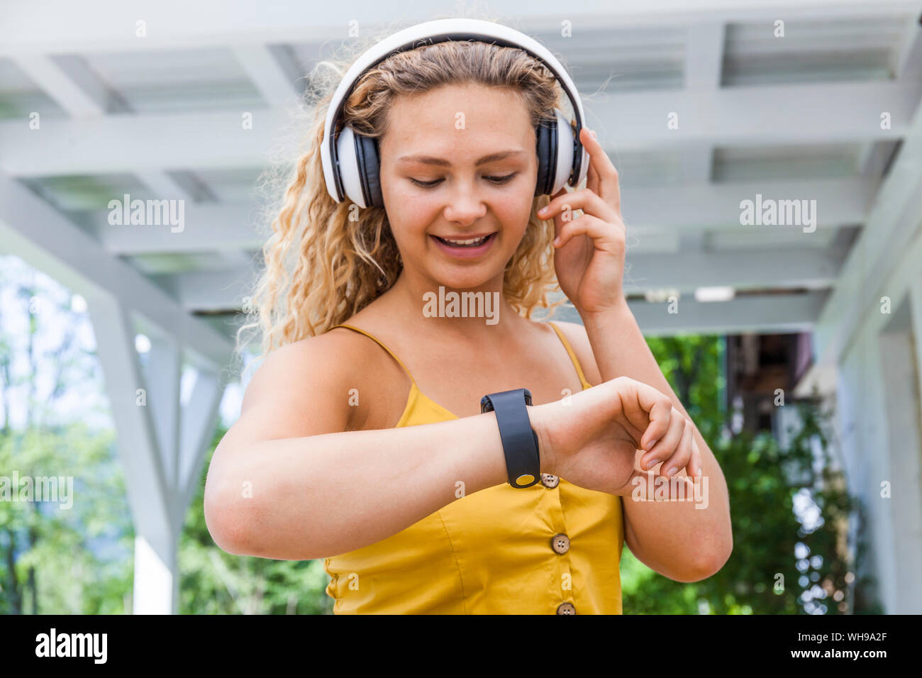 Smiling woman listening to music and looking on smartwatch Stock Photo