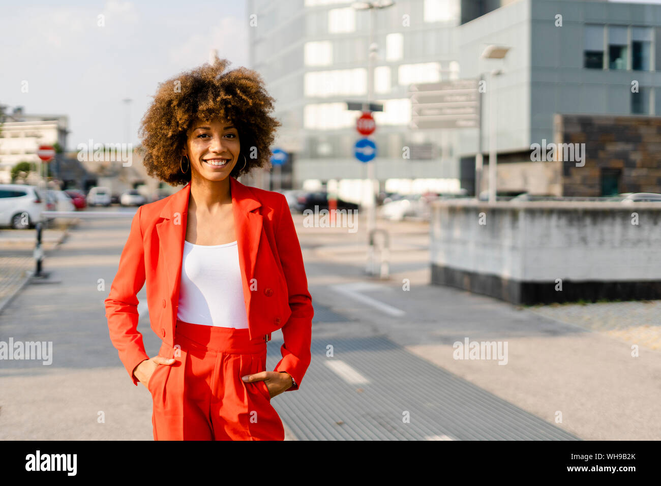 Portrait of smiling young woman wearing fashionable red pantsuit Stock Photo