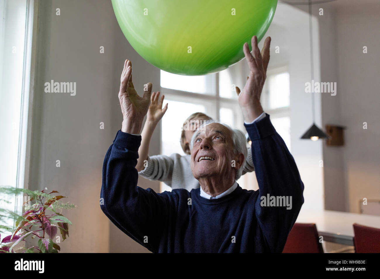 Happy grandfather and grandson playing with balloon at home Stock Photo