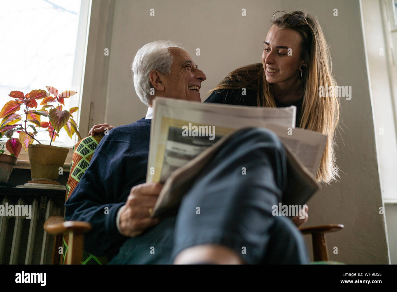 Happy young woman and senior man with newspaper at home Stock Photo