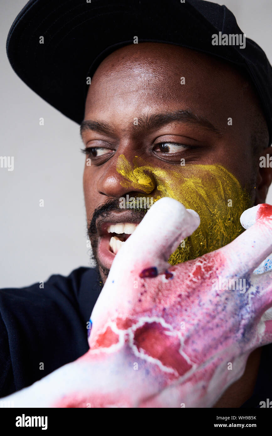Angry artist with hand covered in paint looking at camera Stock Photo