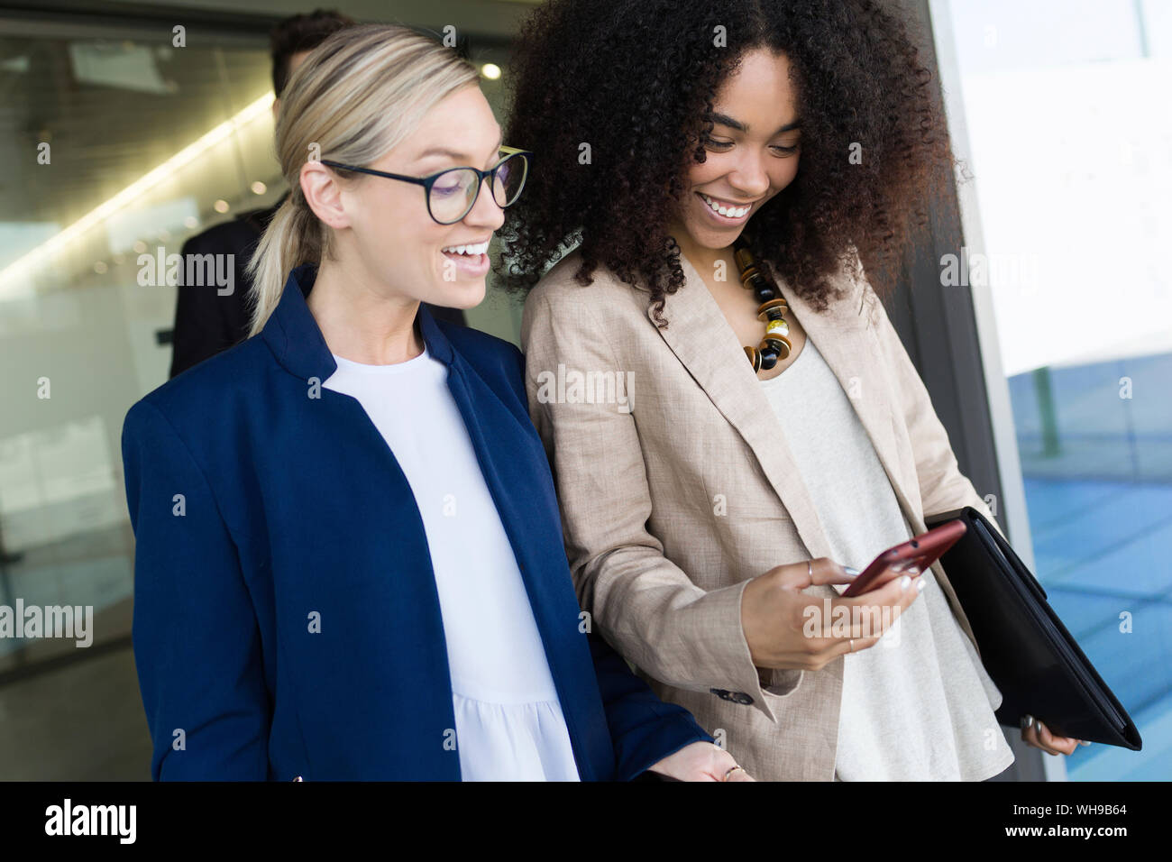 Two happy young businesswomen looking at smartphone Stock Photo