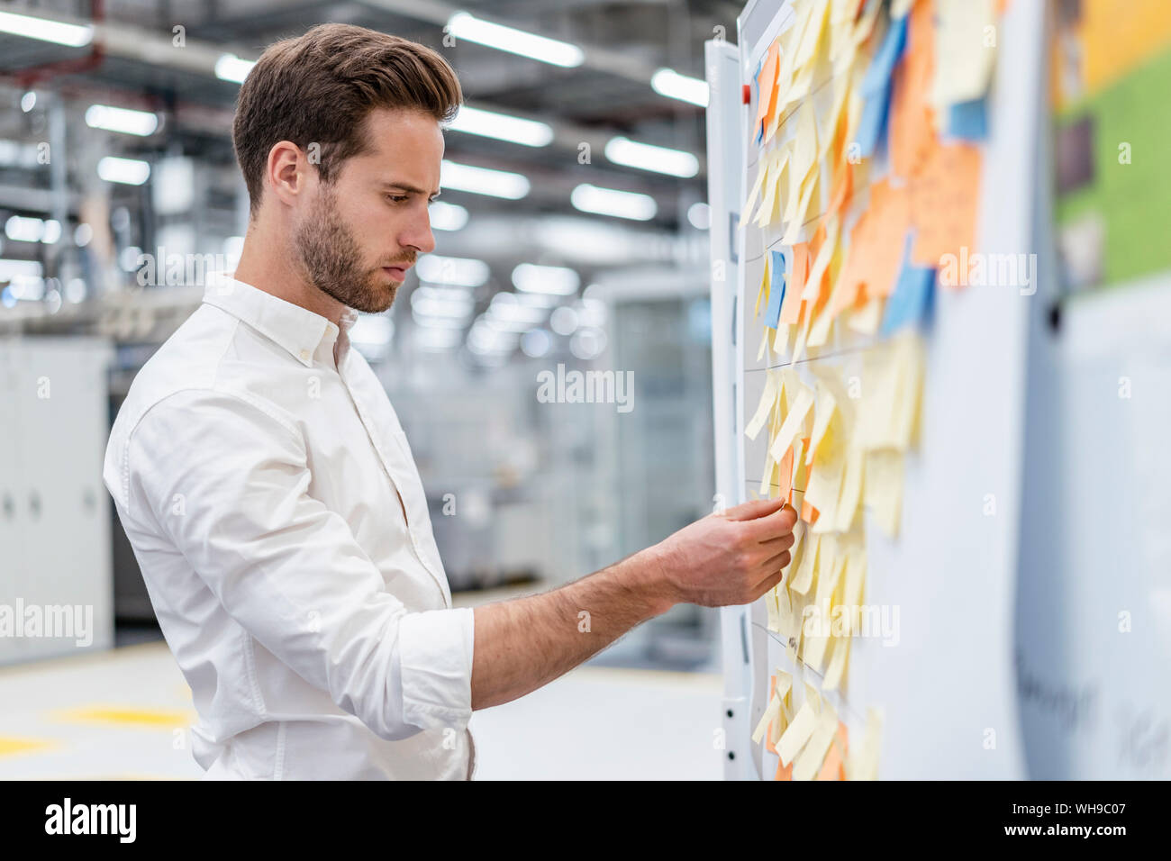Businessman organizing adhesive notes on a board in a factory Stock Photo