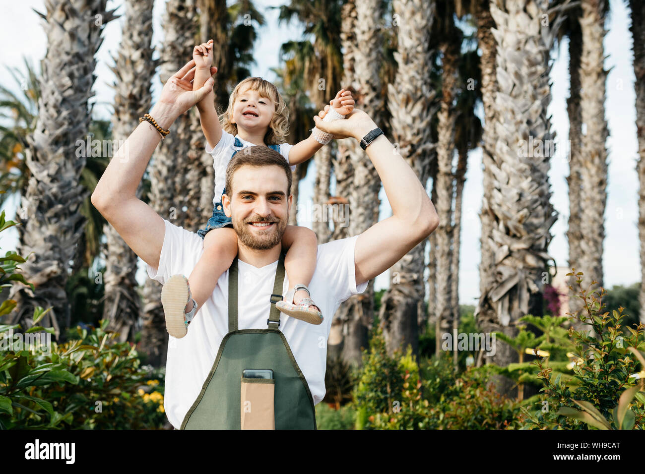 Portrait of a happy worker of a garden center with a girl on his shoulders Stock Photo