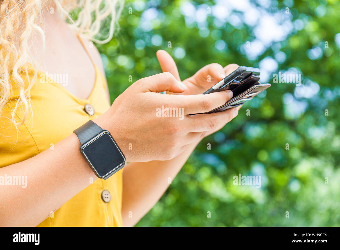 Woman using smartphone, digital clock Stock Photo