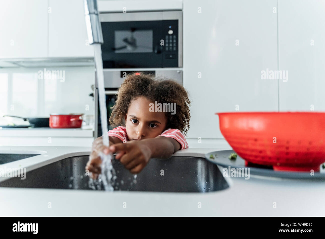 girl washing herself in kitchen sink