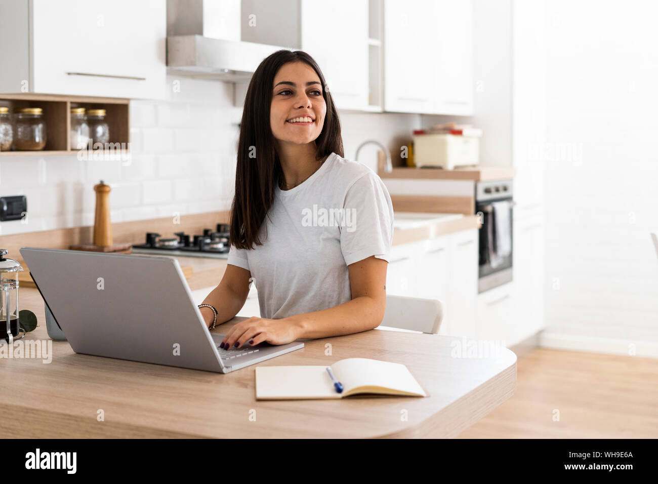 Smiling young woman using laptop at home Stock Photo