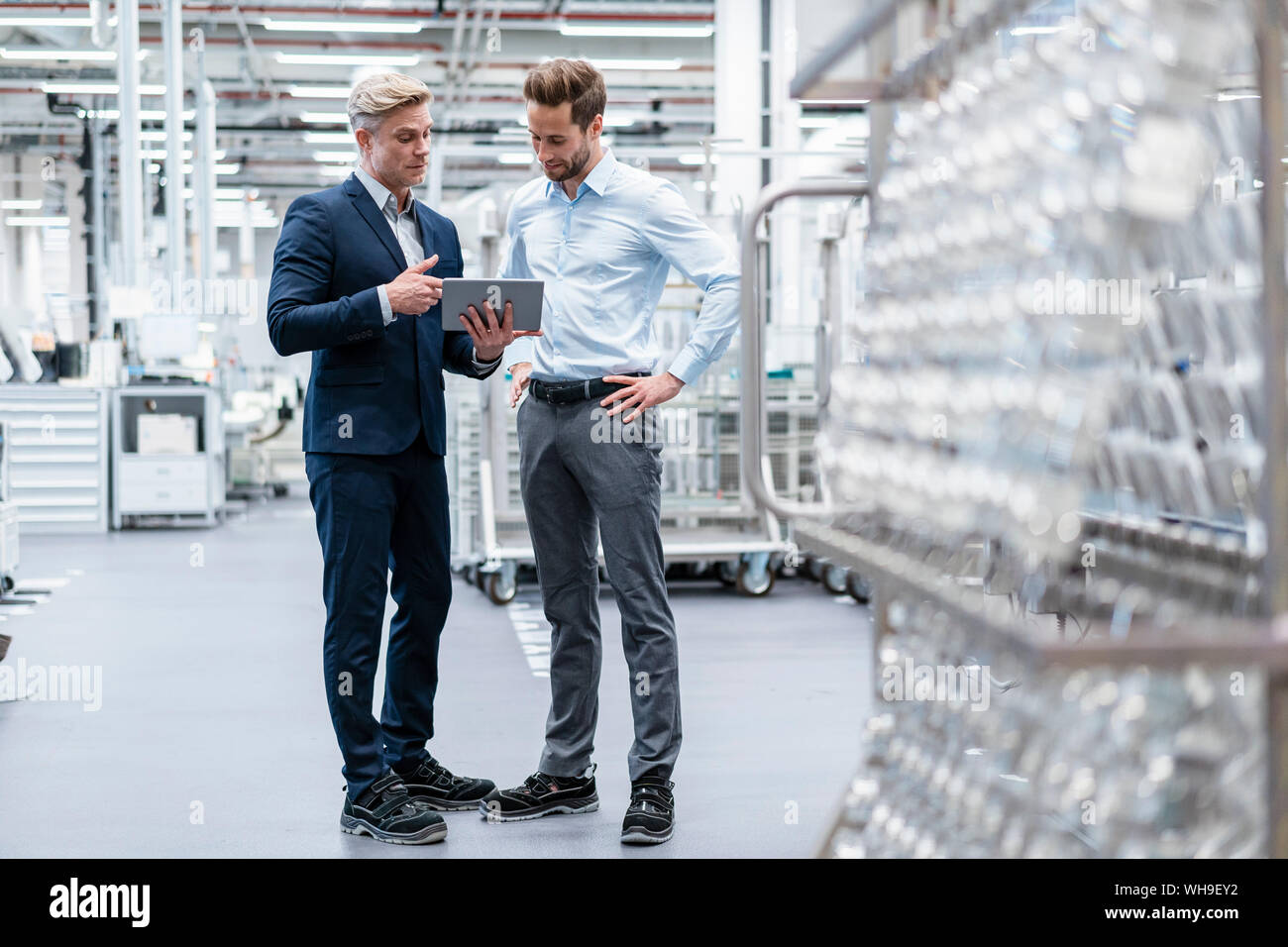Two businessmen with tablet talking in a modern factory Stock Photo - Alamy