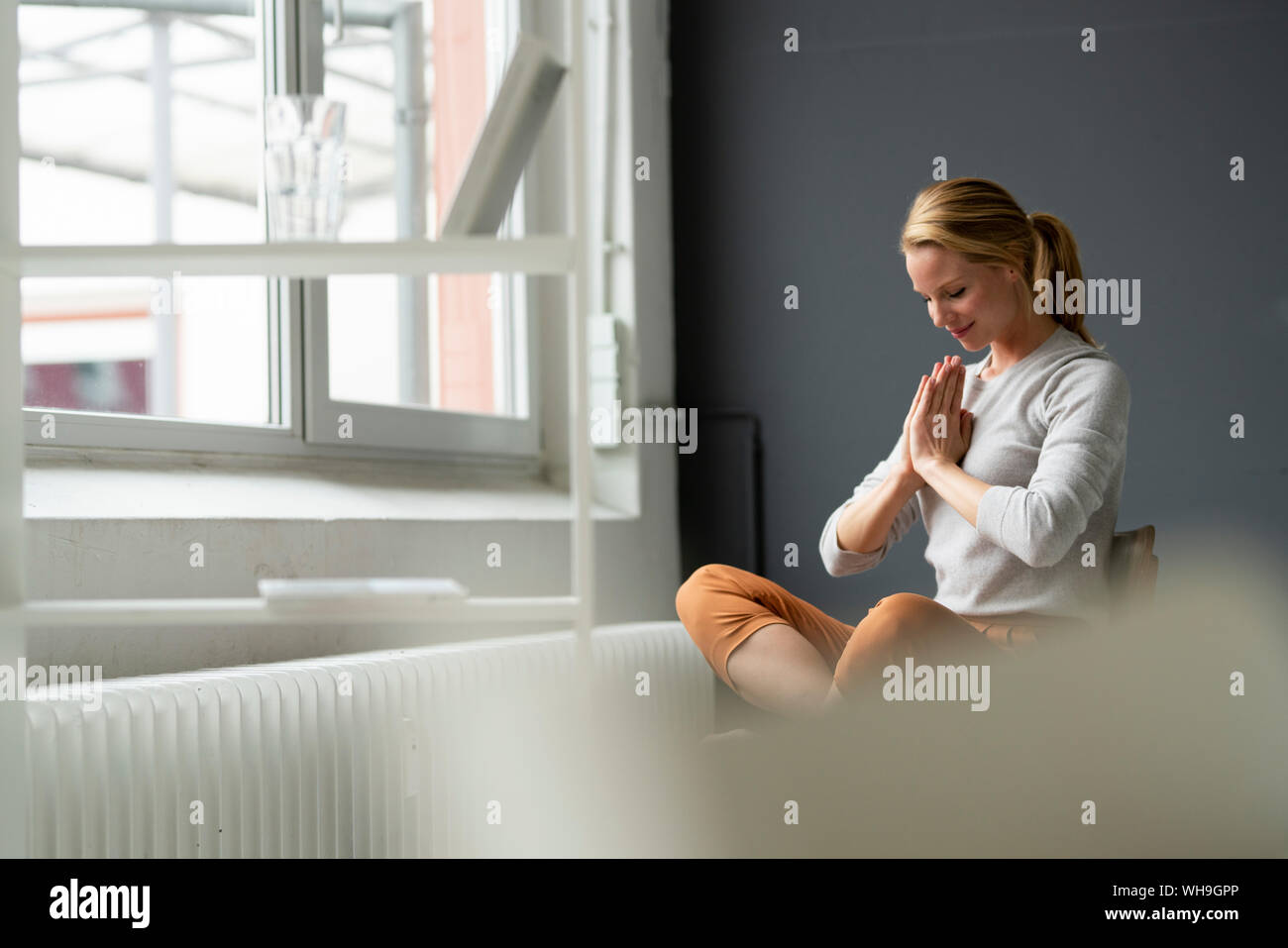 Young woman sitting on chair in office meditating Stock Photo