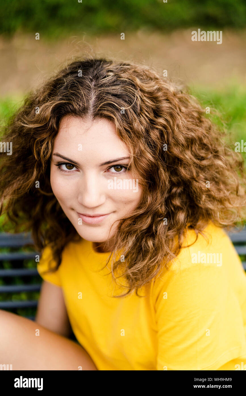 Portrait of smiling young woman on a park bench Stock Photo