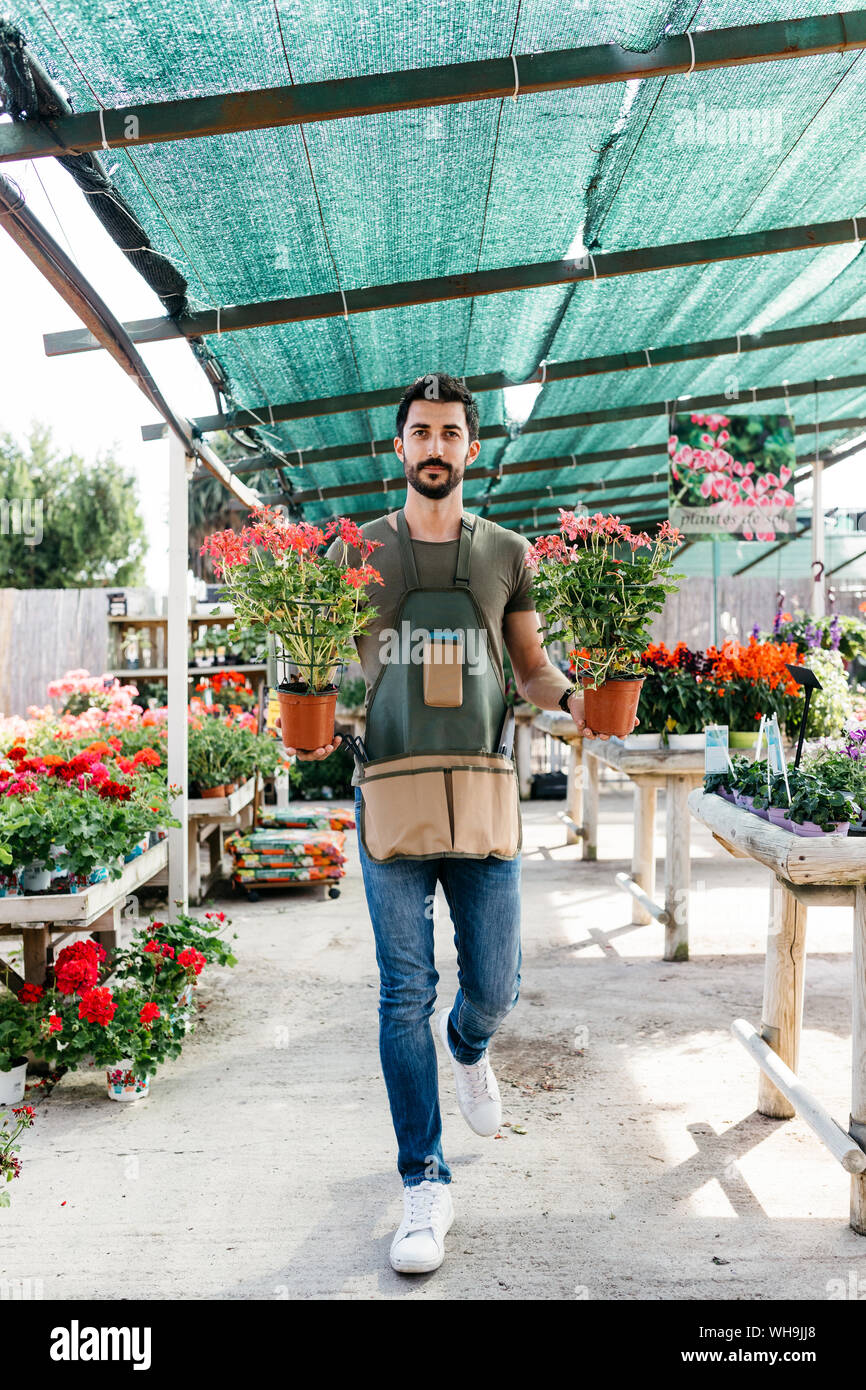 Gardener in a greenhouse holding flowers Stock Photo