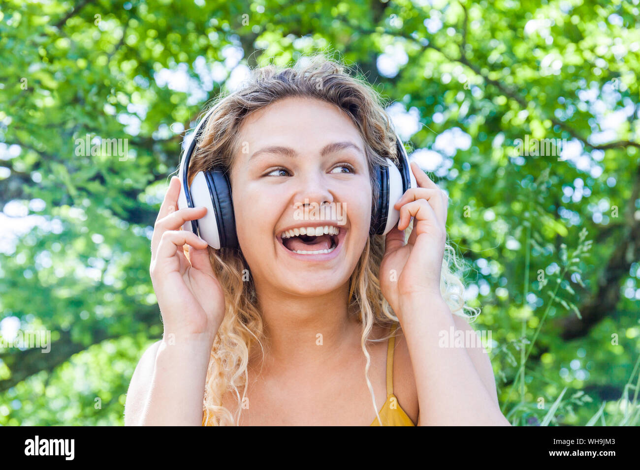 Smiling woman listening to music, looking sideways Stock Photo