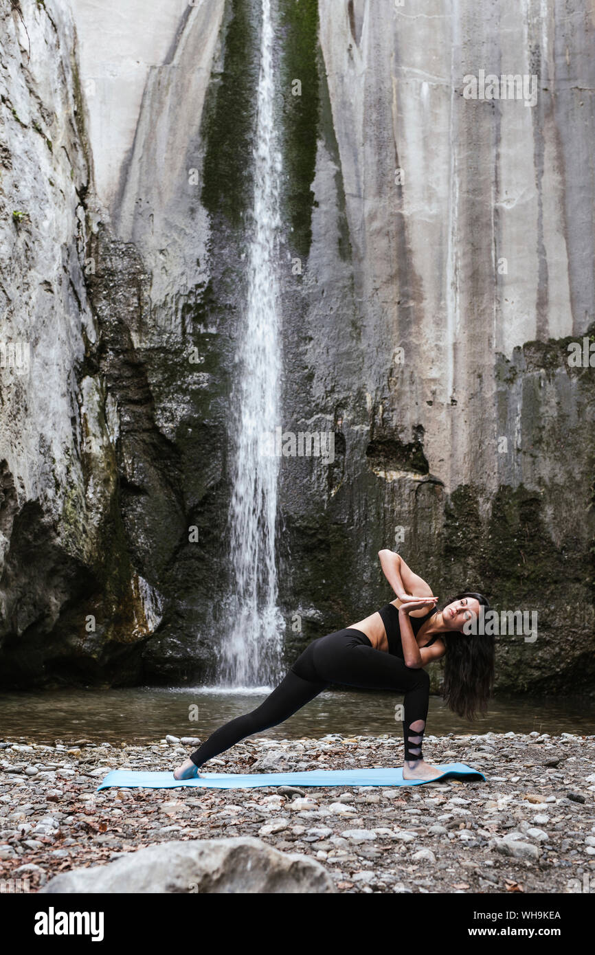 Woman practising yoga at waterfall, triangle pose Stock Photo - Alamy