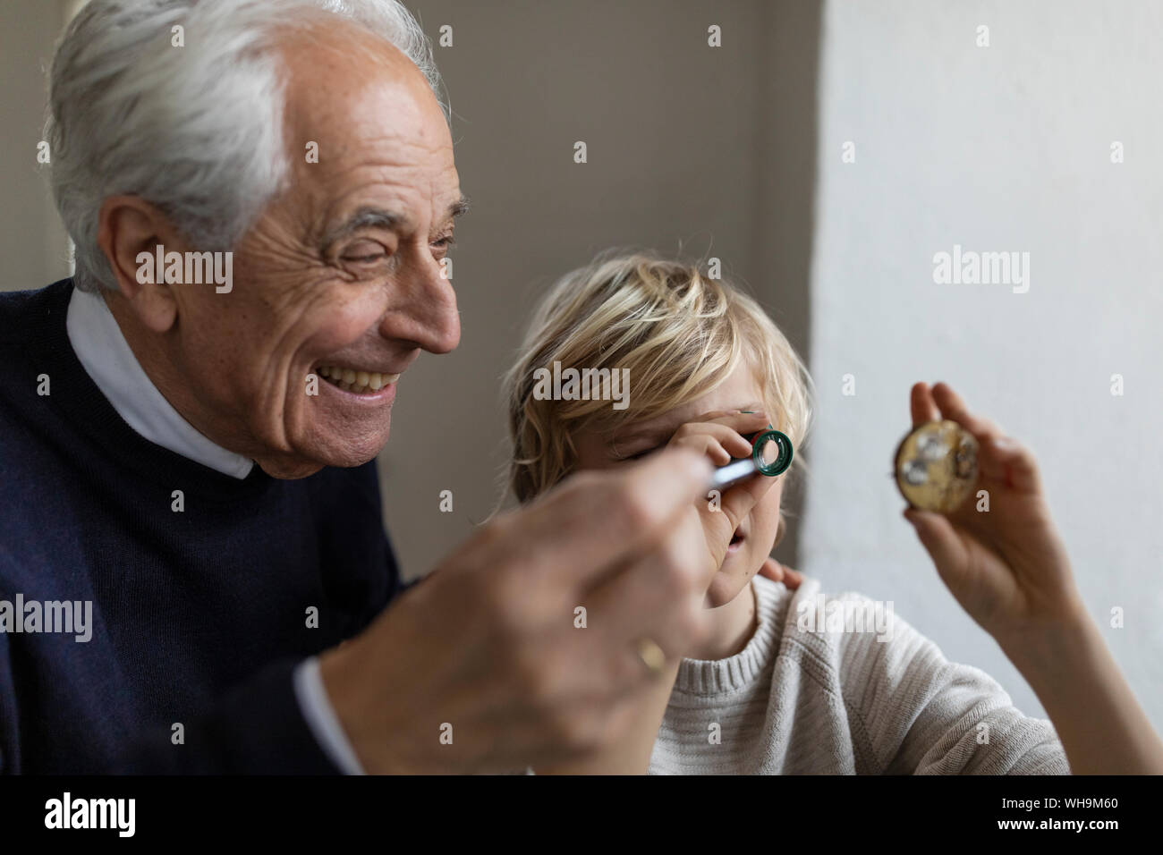 Watchmaker and his grandson looking through ocular Stock Photo