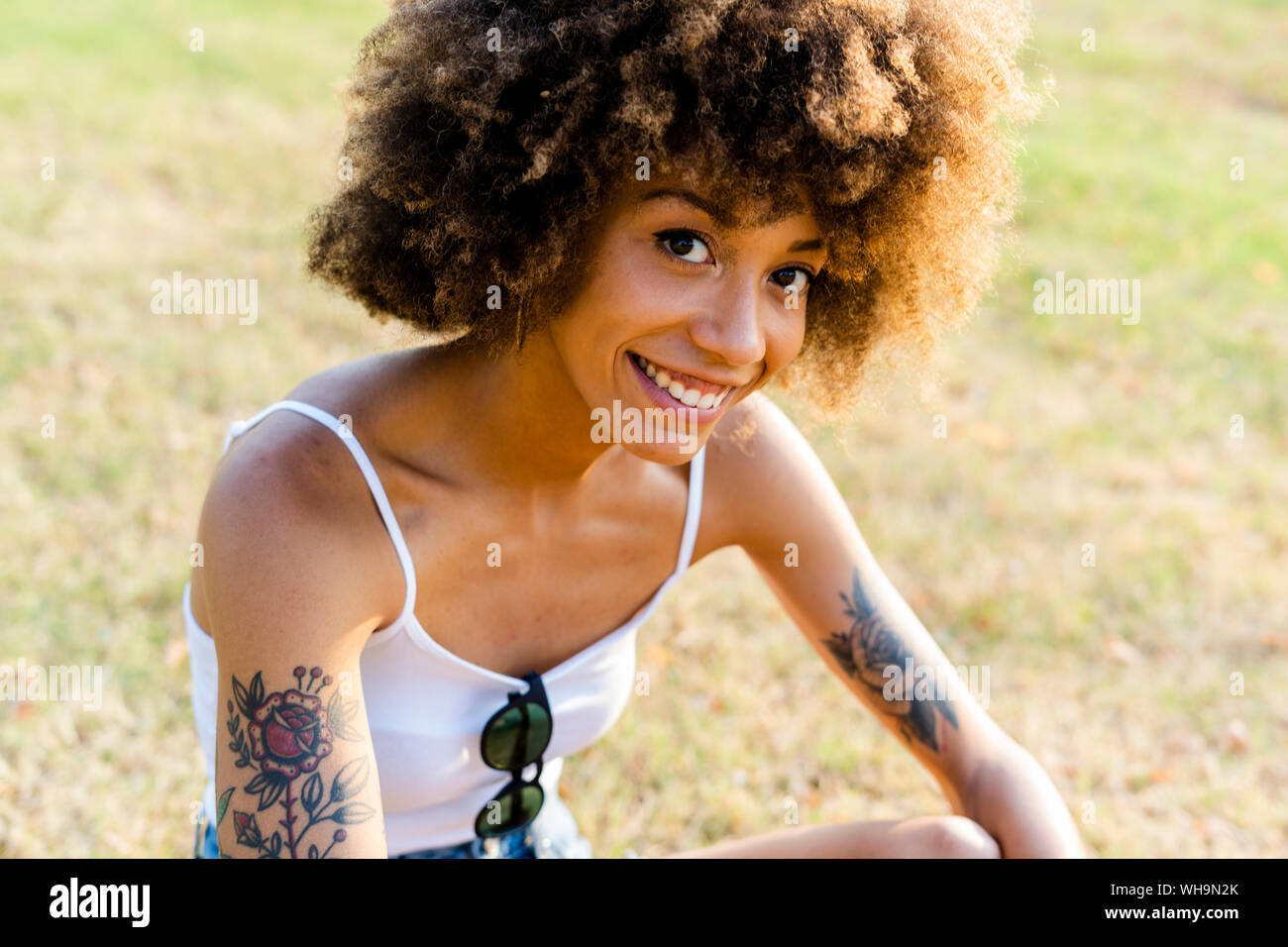 Portrait of tattooed young woman  sitting on a meadow in summer Stock Photo