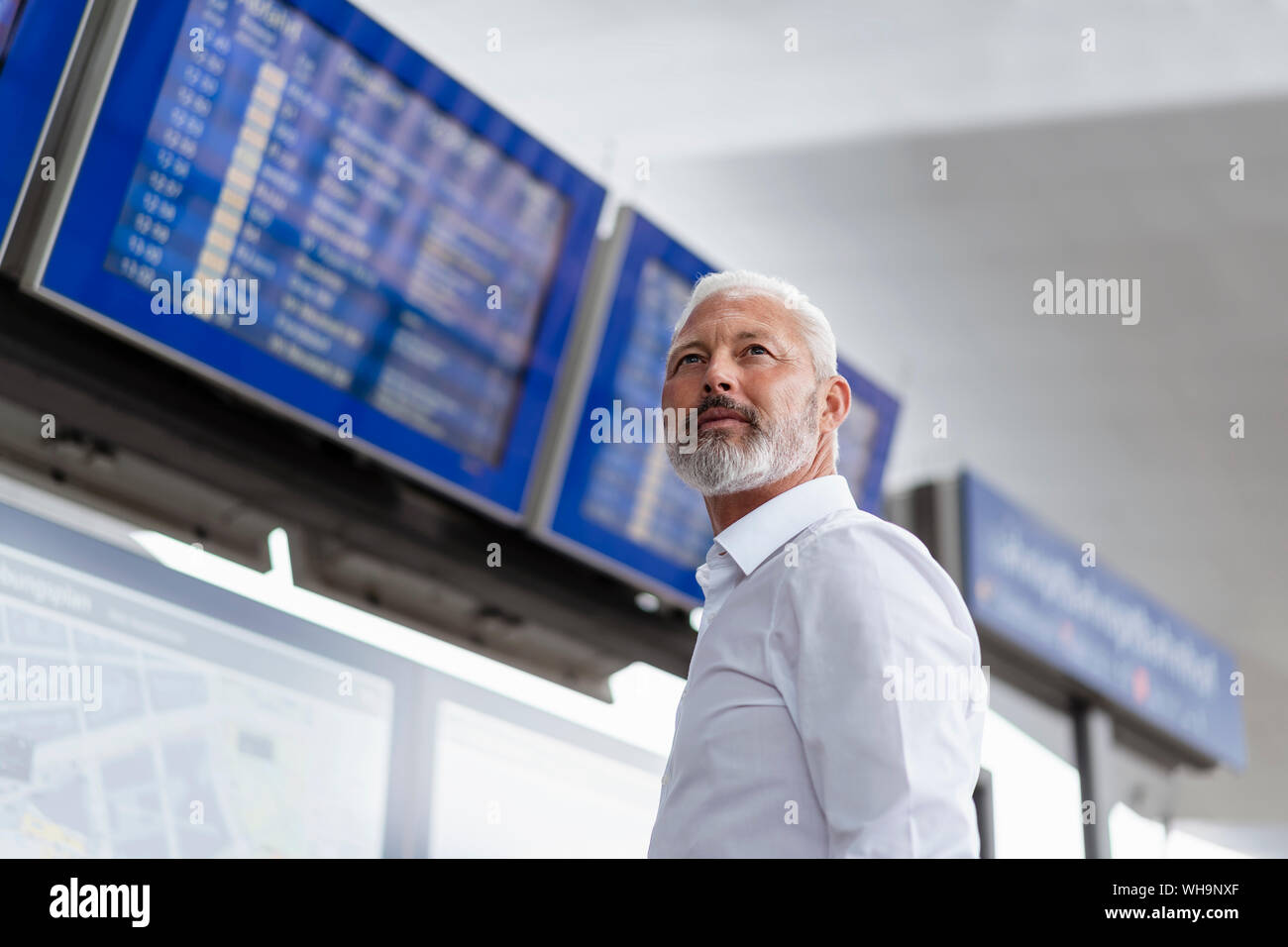 Mature businessman at departures board Stock Photo