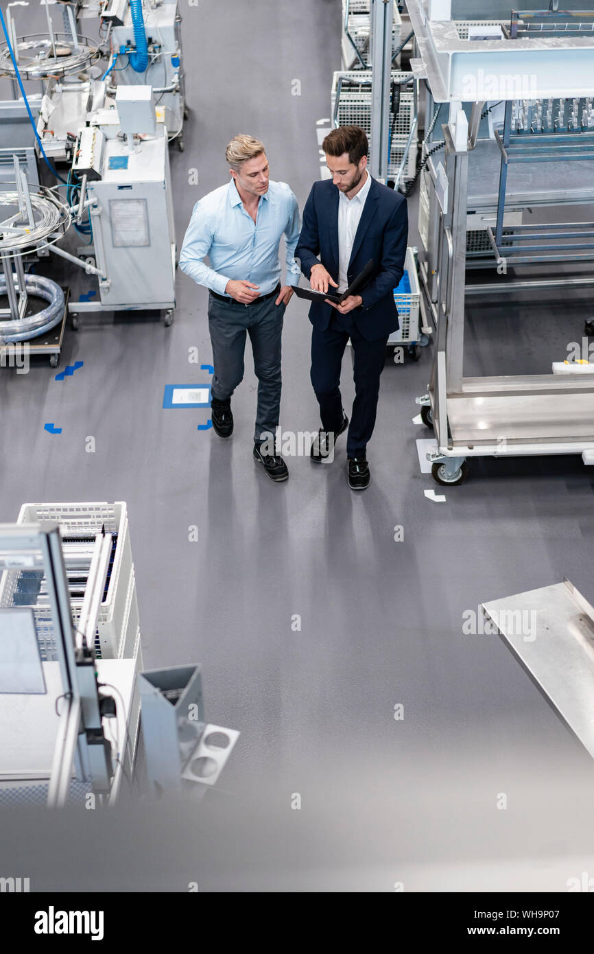 Two businessmen with clipboard talking in a factory Stock Photo - Alamy