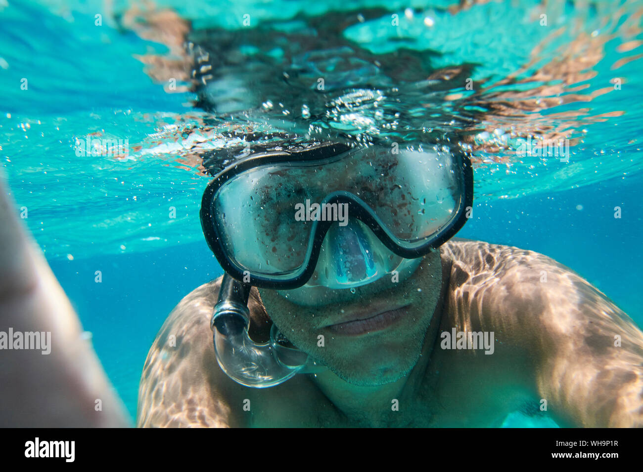 Portrait of man with diving goggles and snorkel taking selfie under water Stock Photo