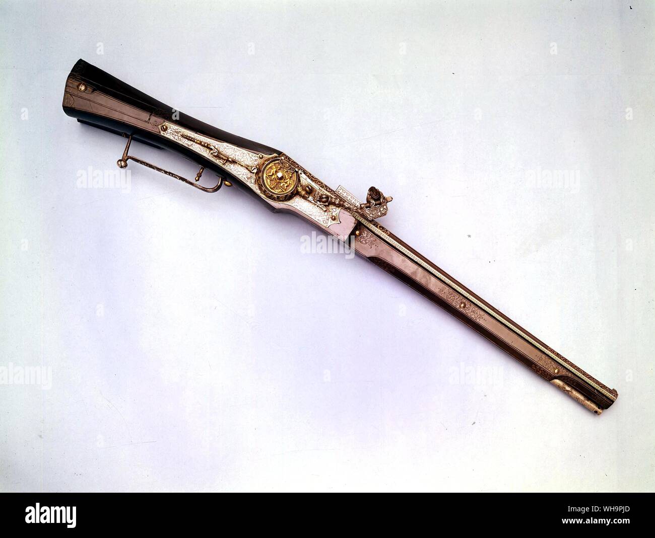 Wheel lock carbine one of the finest made in the early period of the wheel lock. The barrel is damascened along its whole length with arabesques and geometrical patterns in gold silver. The lock plate with chiseled dog is decorated en suite The wheel cover is cast and pierced with figures of cupids in gilt bronze. The stock is overlaid with ebony engraved with gilt arabesques Stock Photo