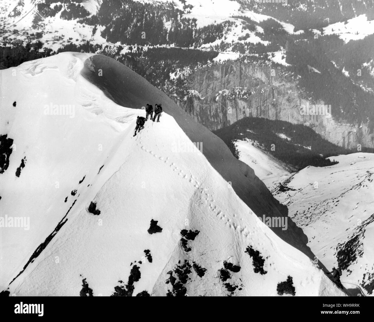 The end of the route for three of the climbers as they wait for their fellow mountaineer to finish the last few feet of the climb to the summit of the Eiger Mountain. 12th March 1961. Stock Photo