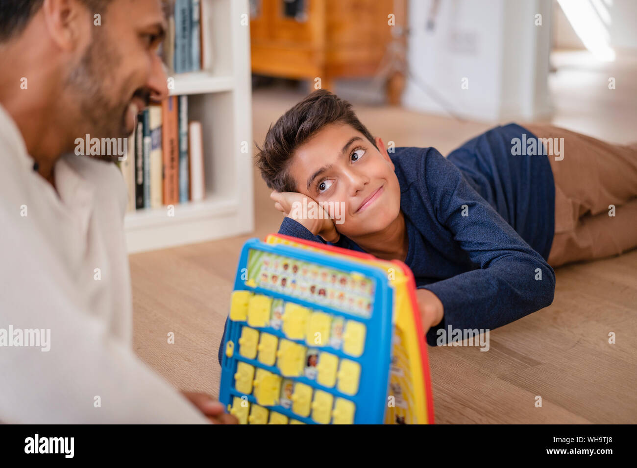 Father and son lying on the floor at home playing a game Stock Photo