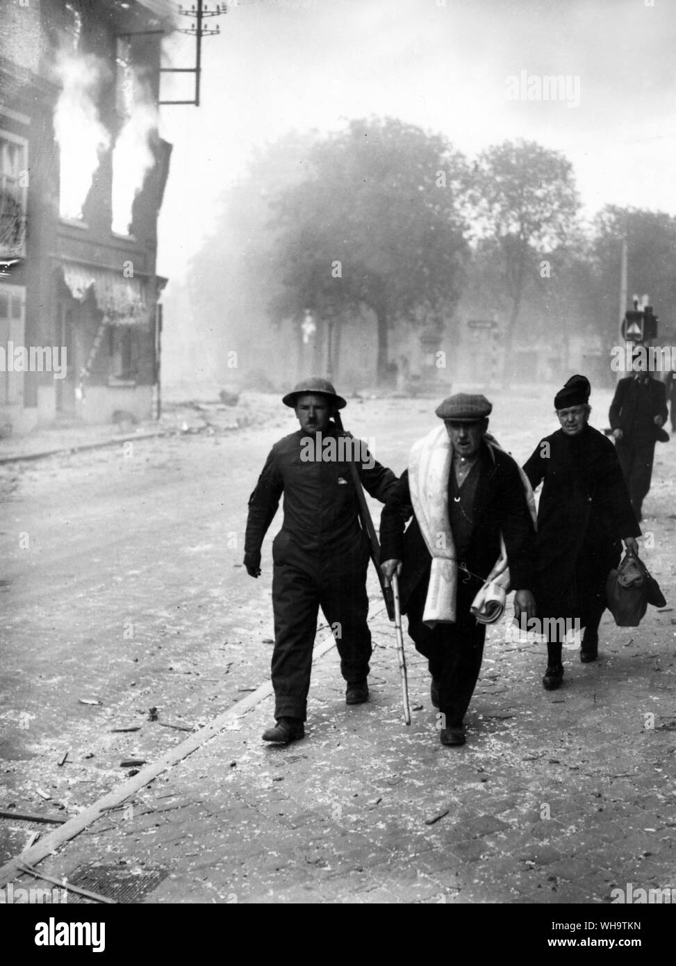 WW1/France: An allied soldier helps civilians away from burning buildings. Stock Photo
