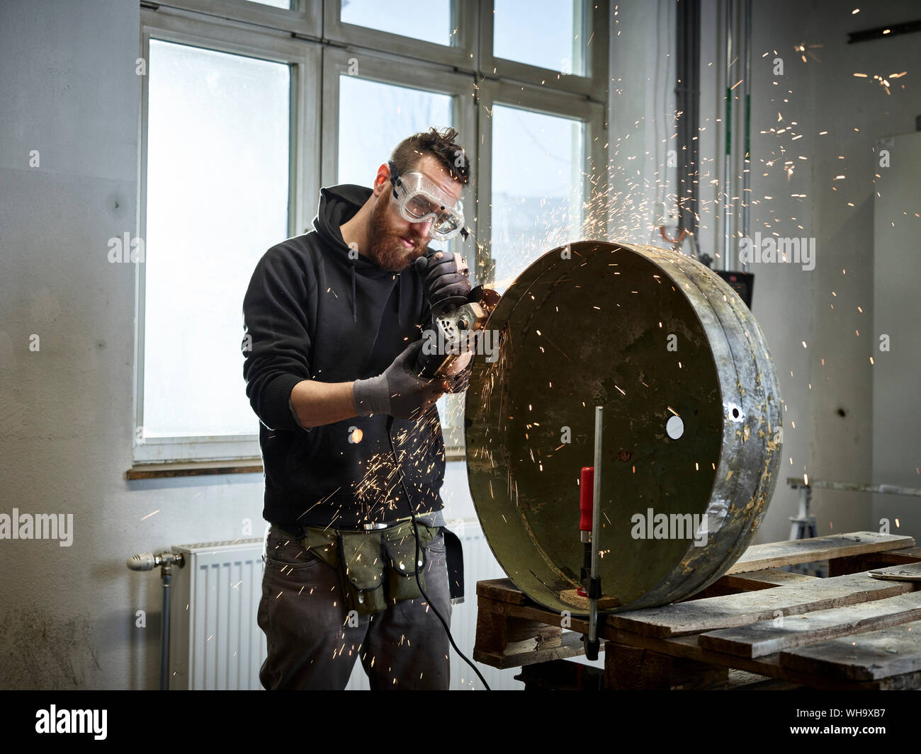 Man working on metal container with grinder Stock Photo