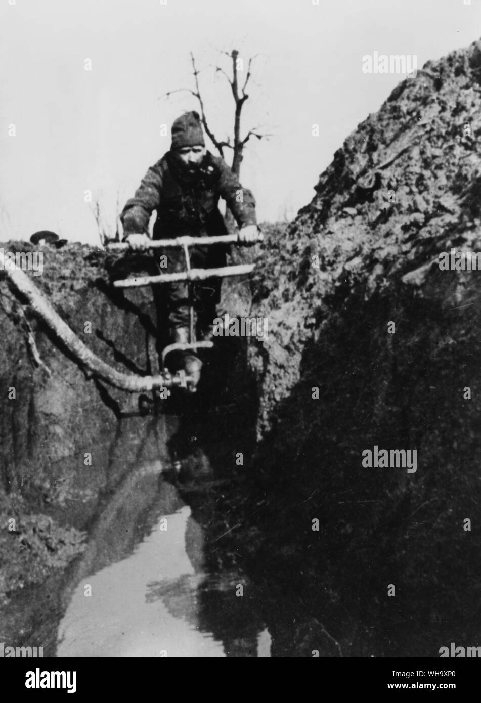 WW1: Man pumping water from a flooded trench, Western Front, 1914. Stock Photo