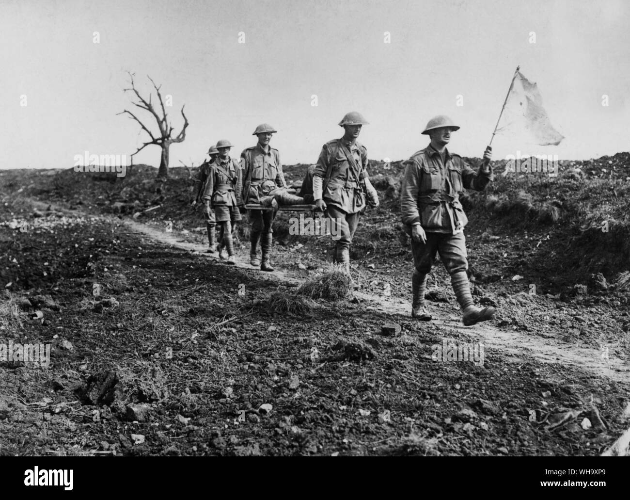 WW1: British troops carry a wounded soldier off the battle-field on a stretcher. The soldier in front carries a white flag. Stock Photo