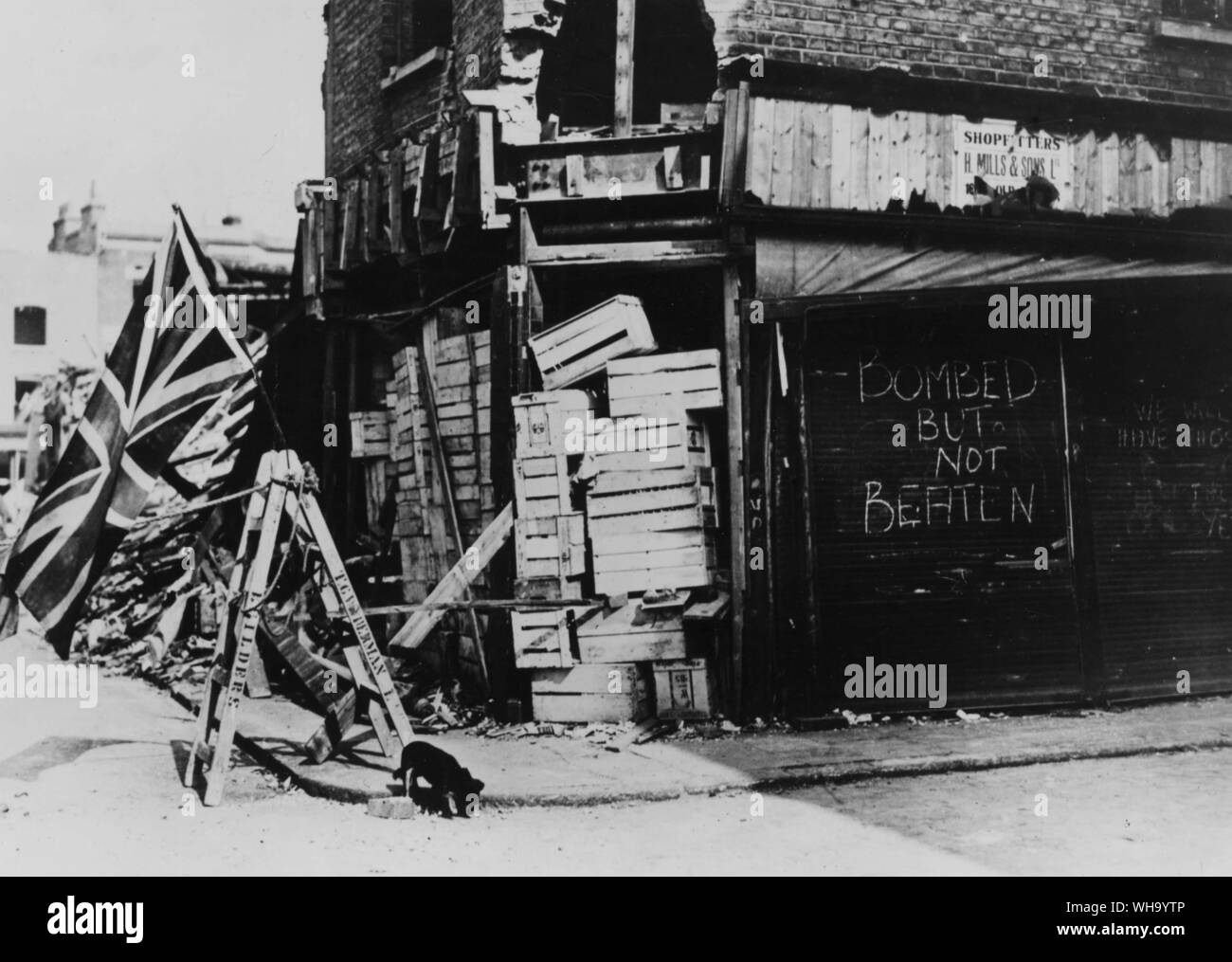 WW2/ Battle of Britain: Debris of a shop, but with a defiant sign saying: 'Bombed But Not Beaten'. Stock Photo