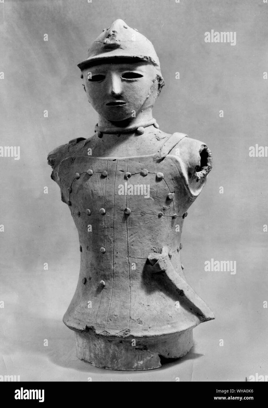 A Japanese haniwa figure of red clay, showing a man in armour; probably