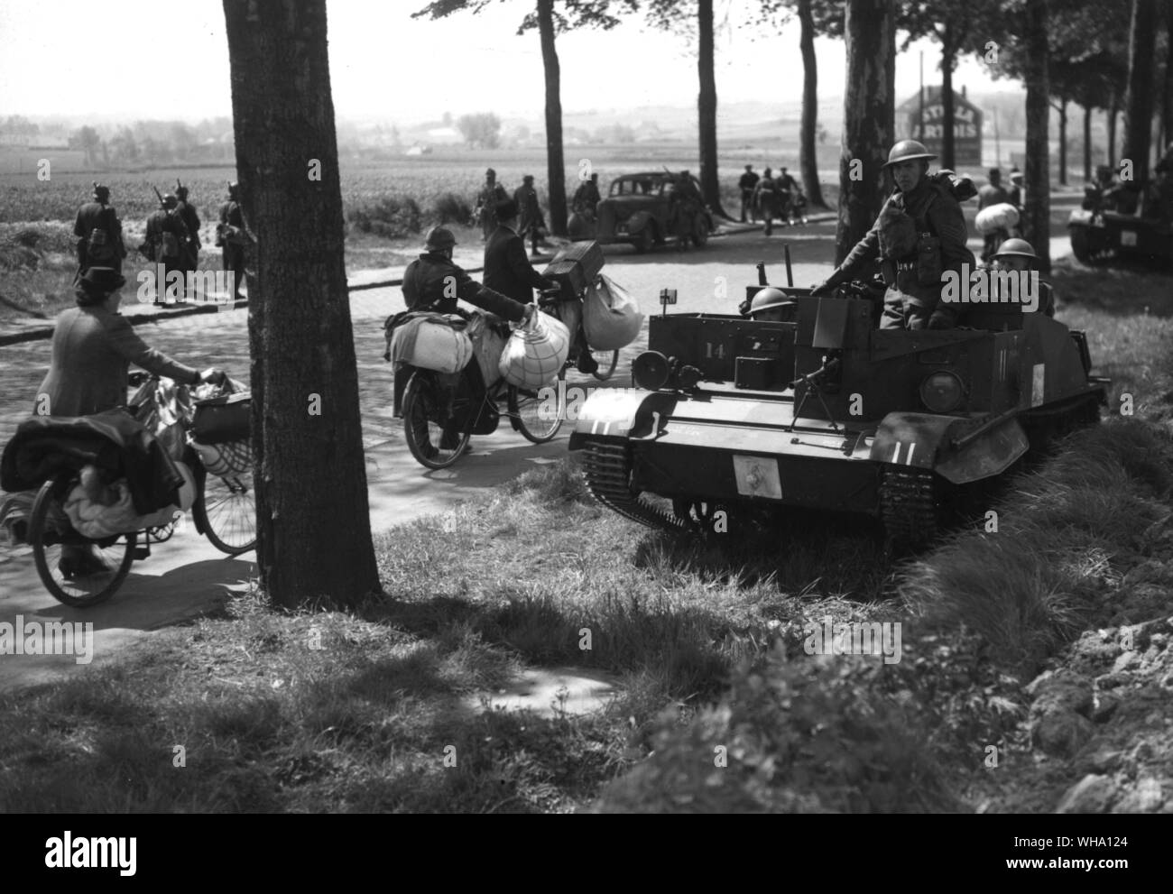 WW2: Brussells-Louvain. British troops halted by the wayside with Bren carriers, while refugees file past. Stock Photo