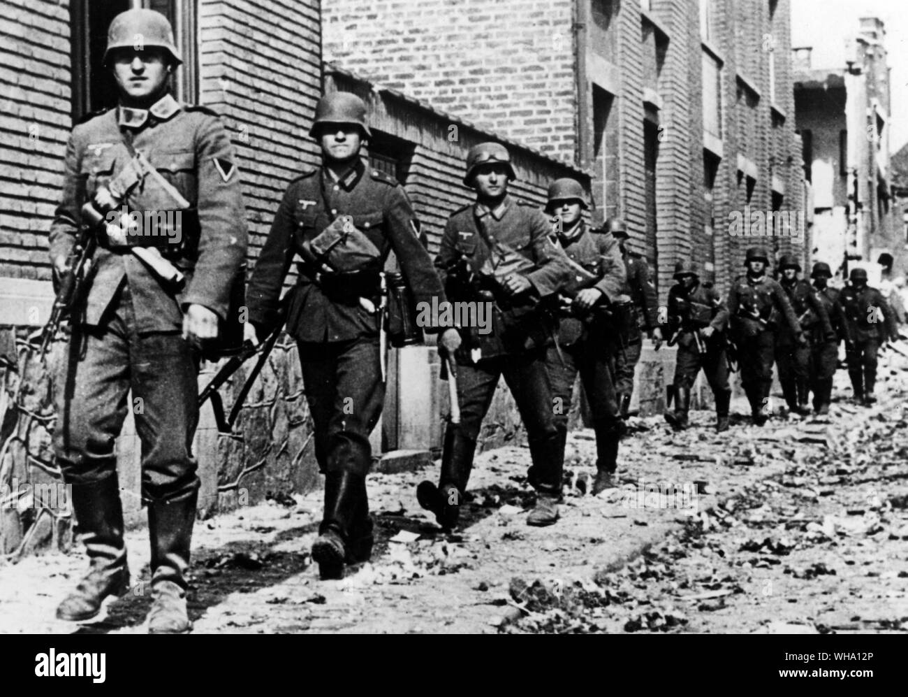 WW2: German troops. Rifle section of motorised infantry unit moving up through a Belgian village street, May 1940. Stock Photo