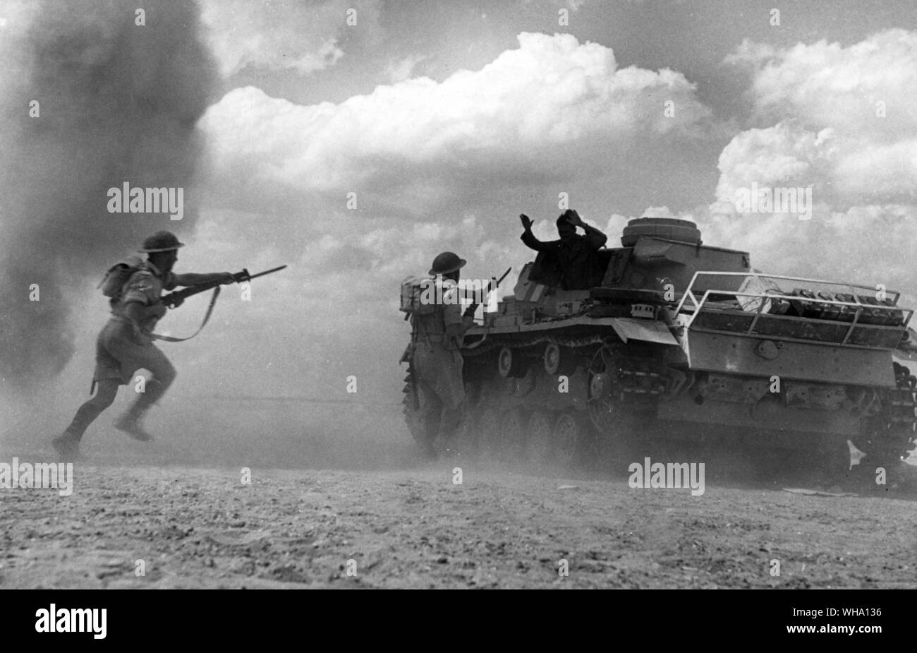 WW2: One member of a knocked-out tank surrenders as British infantry rush the tank. Alamein. Stock Photo