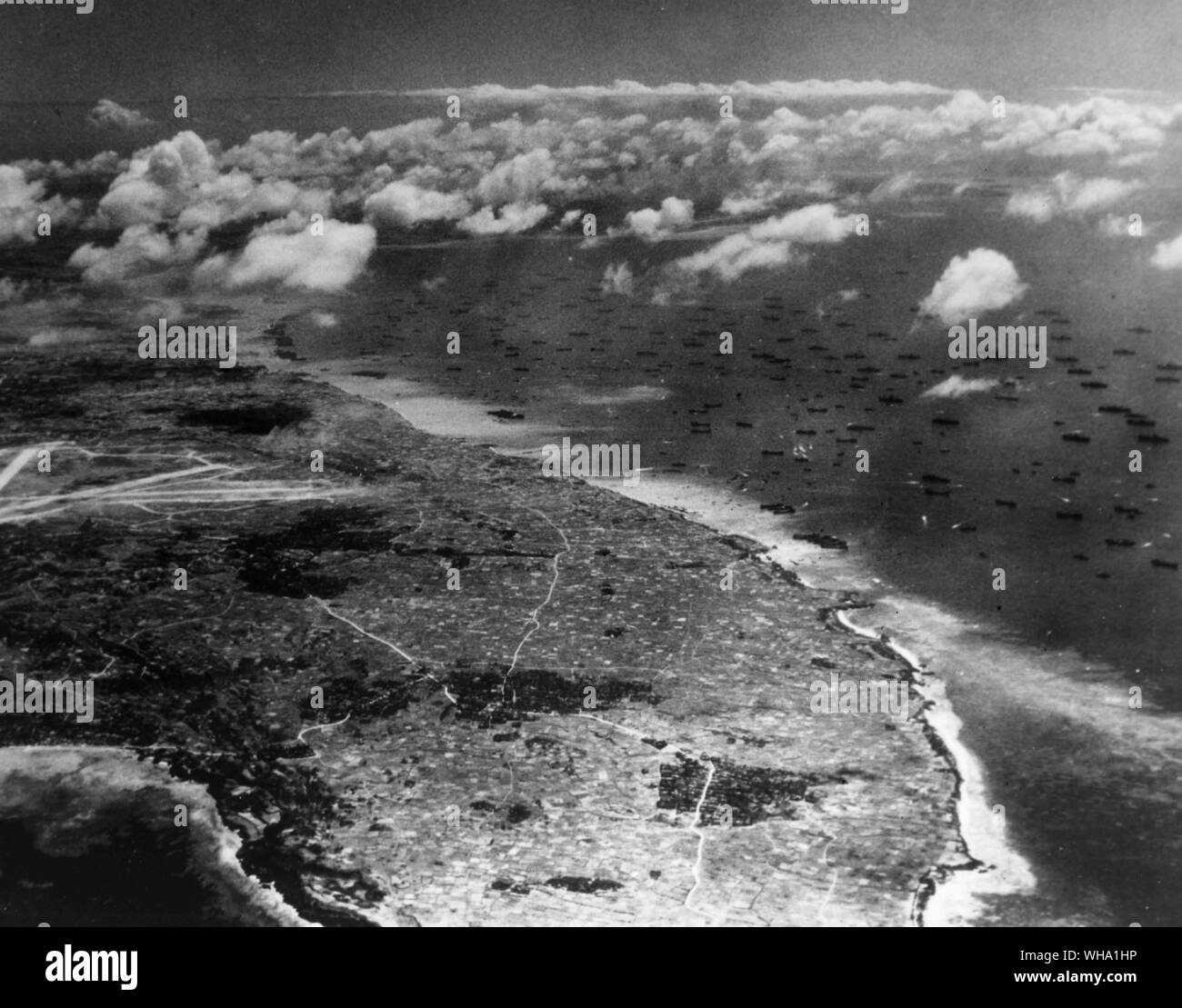 WW2: Invasion ships stand off the island of Okinawa, Ryjkyu Islands, on D plus two day. In the left centre of the photo is the airfield of Yontan which fell to the American troops on the first day of the invasion. Aerial 5th April 1945. Stock Photo