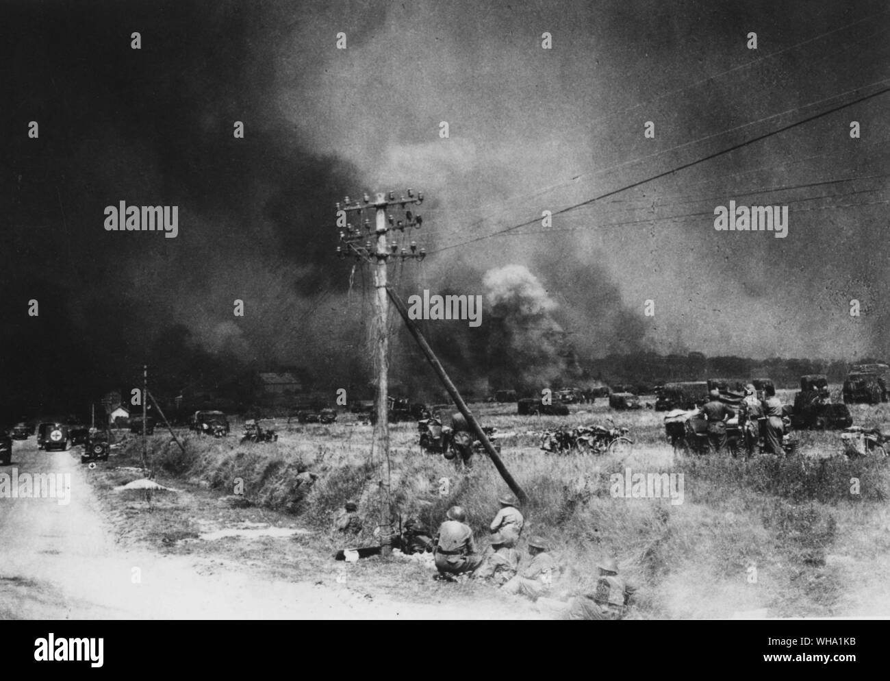 WW2: Advance by Canadian Army with British troops towards Falaise, France. Photo shows fires caused by bombing with transport and men taking cover on Caen-Falaise road. 11th August 1944. Stock Photo