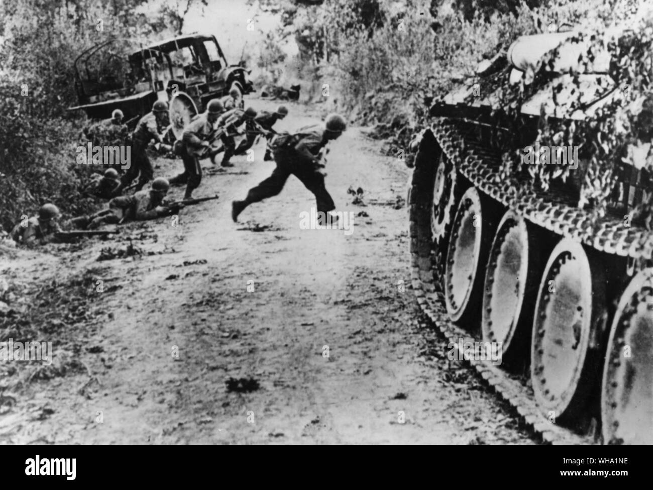 WW2: Infantry of the US 29th (Blue and Gray) Division dash across an expose road near St Andre de l'Epine. The bocage country provided excellent cover for the German troops defending St Lo. Stock Photo