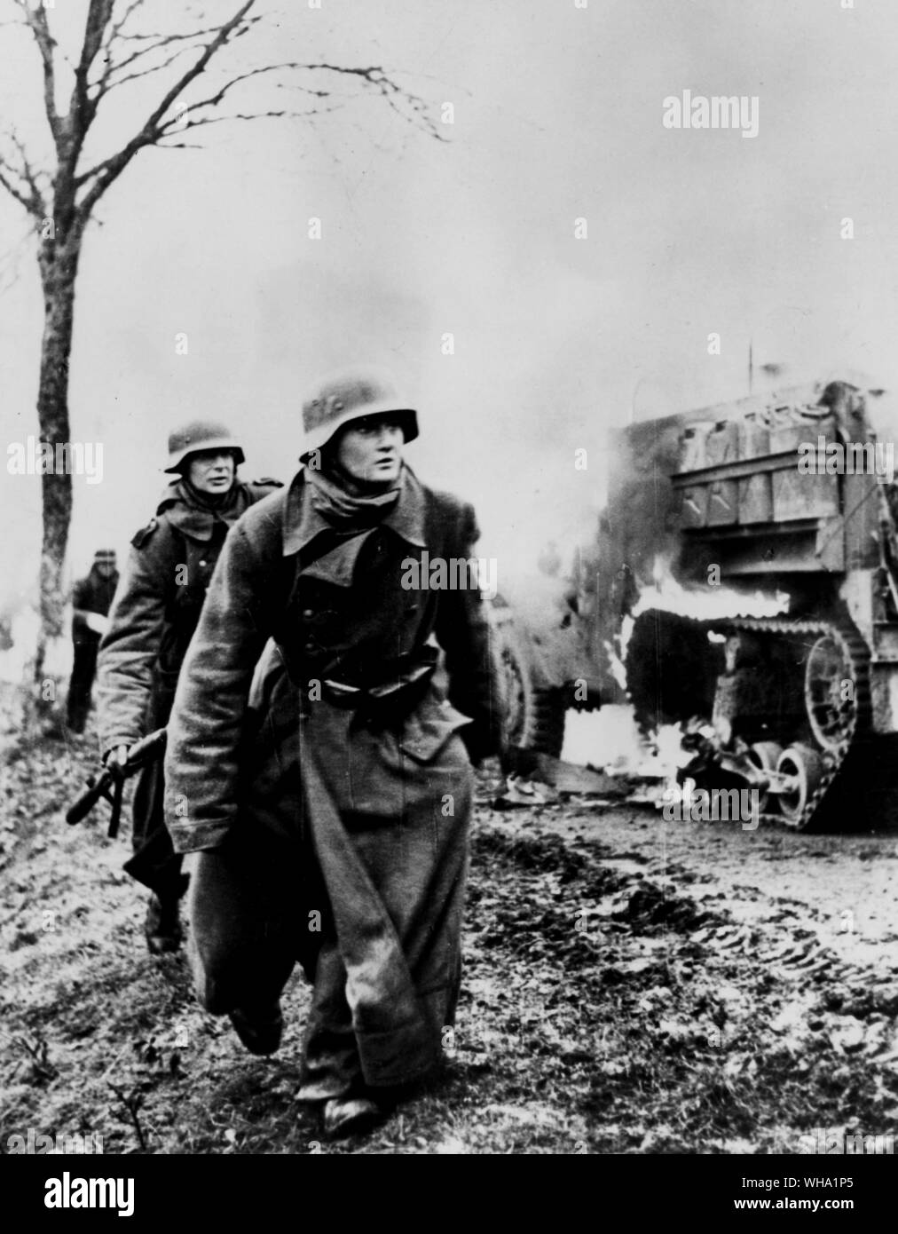 WW2: German troops bypass burning American half-track vehicle. Dec. 1944 - Jan.1945. Ardennes campaign. Stock Photo