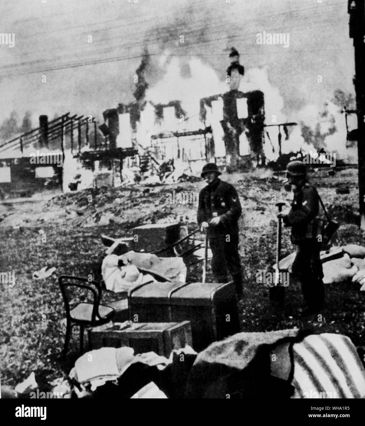 WW2: German invasion of Russia. Nazi pillagers survey the spoils, while a home burns behind them. Stock Photo