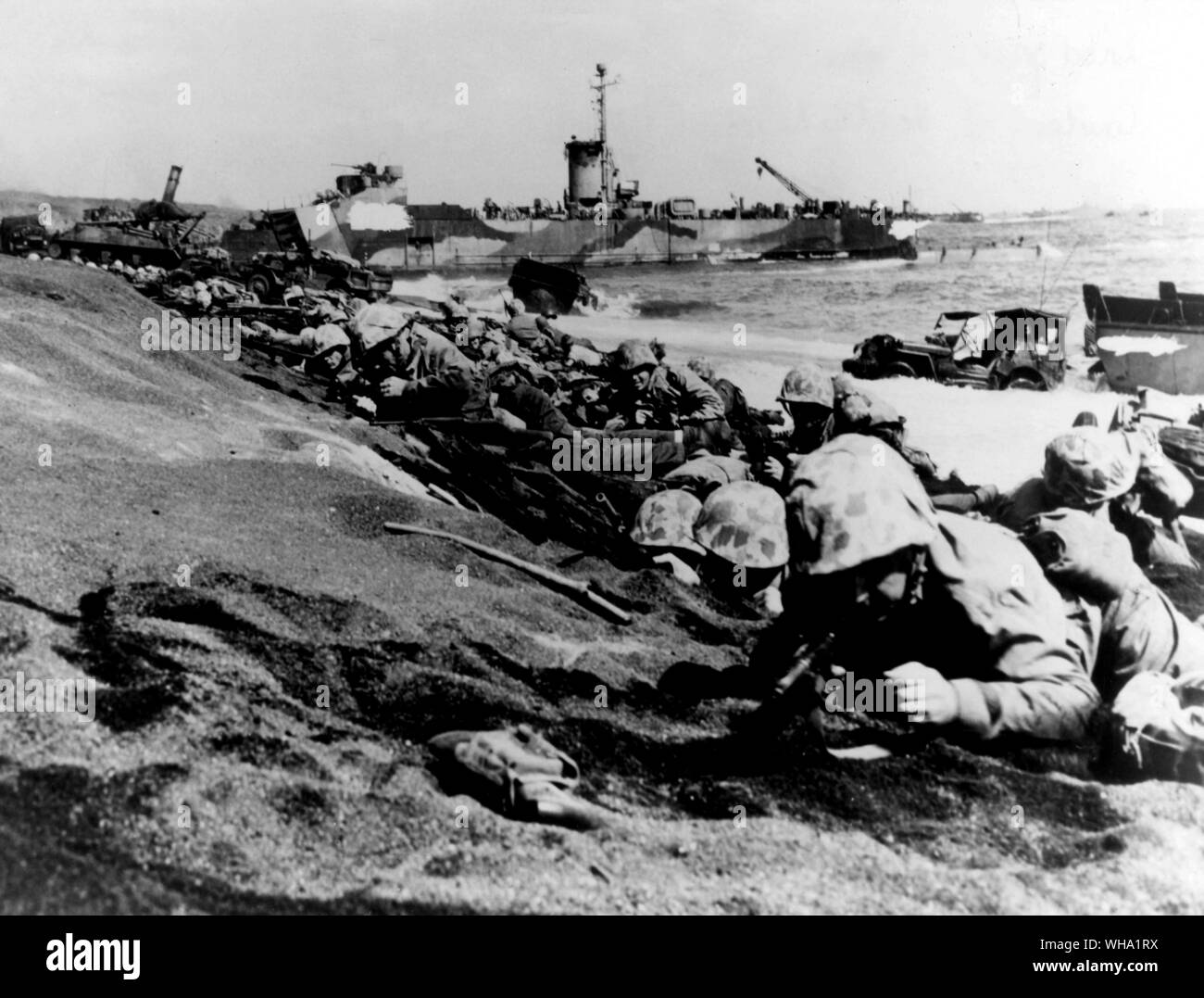 WW2: Fourth Marine Division moving up the beach of Iwo Jima on D-Day, 19th Feb. 1945. Making their fourth amphibious assault in 12 months, the veteran fighters are ready to secure the right flank of the initial beach head. An LSM is in the background. Stock Photo