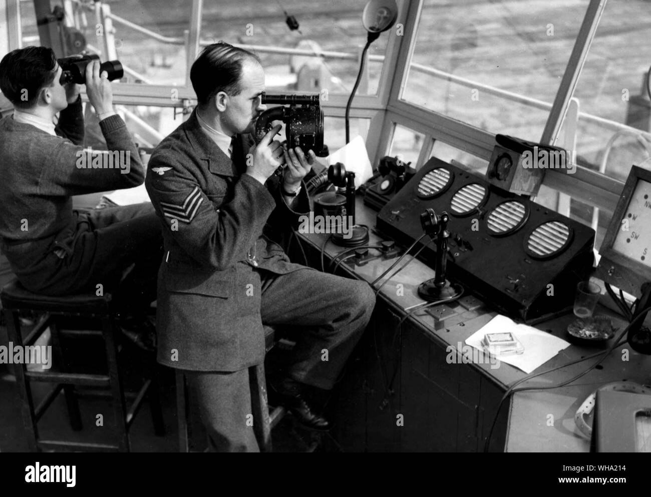 WW2: Allied Forces. An RAF sergeant in an air traffic control tower uses binroculars to lookinto the distance. Stock Photo