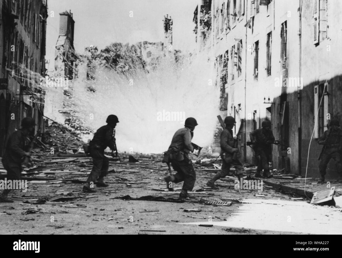WW2: White phosphorus shells explode as US soldiers dash across a street in Brest to drive Nazi snipers from their hideouts (undated). Stock Photo