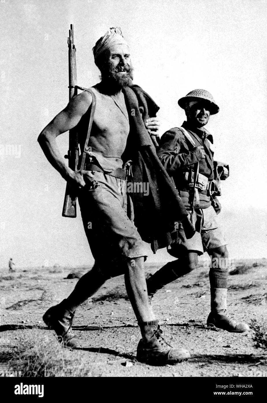 WW1: This bearded warrior wore no shirt but carried his great coat as he marched in with a British soldier. Stock Photo