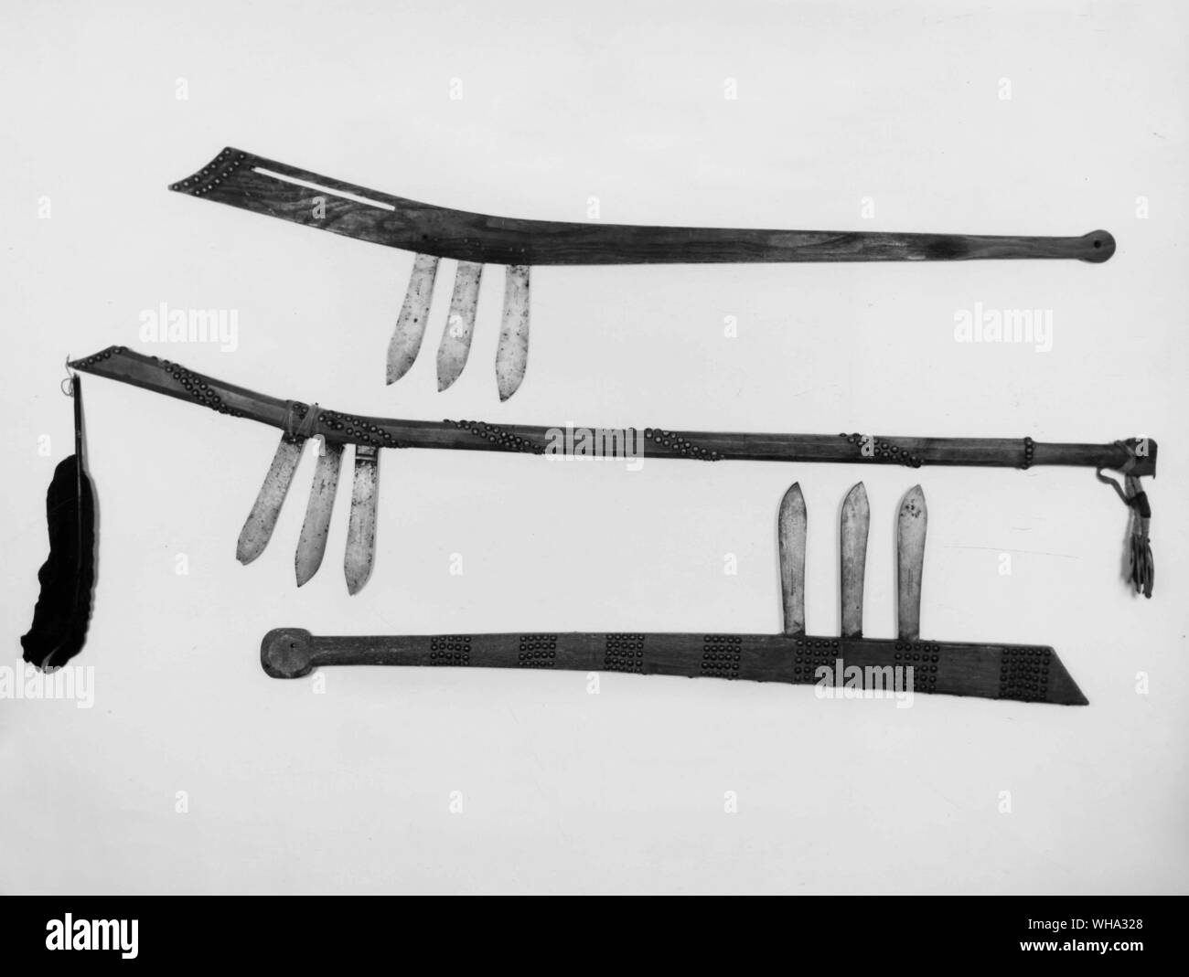 Gun stock clubs. Top to Bottom: - with three knife blades, Gros Ventras; - with three knife blades, decorated with brass nails and feather, 47.5 inches long, Blackfoot; - with three knife blades, decorated with brass nails, Sioux. Stock Photo