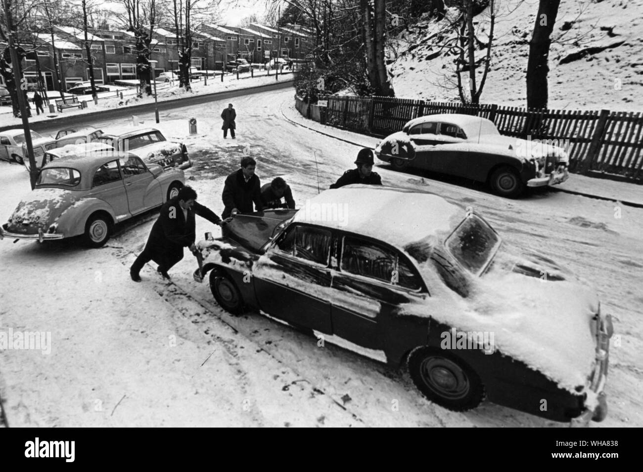 Traffic chaos caused by snow. A policeman helps to move a car trapped in the snow. 8th December 1967 Stock Photo