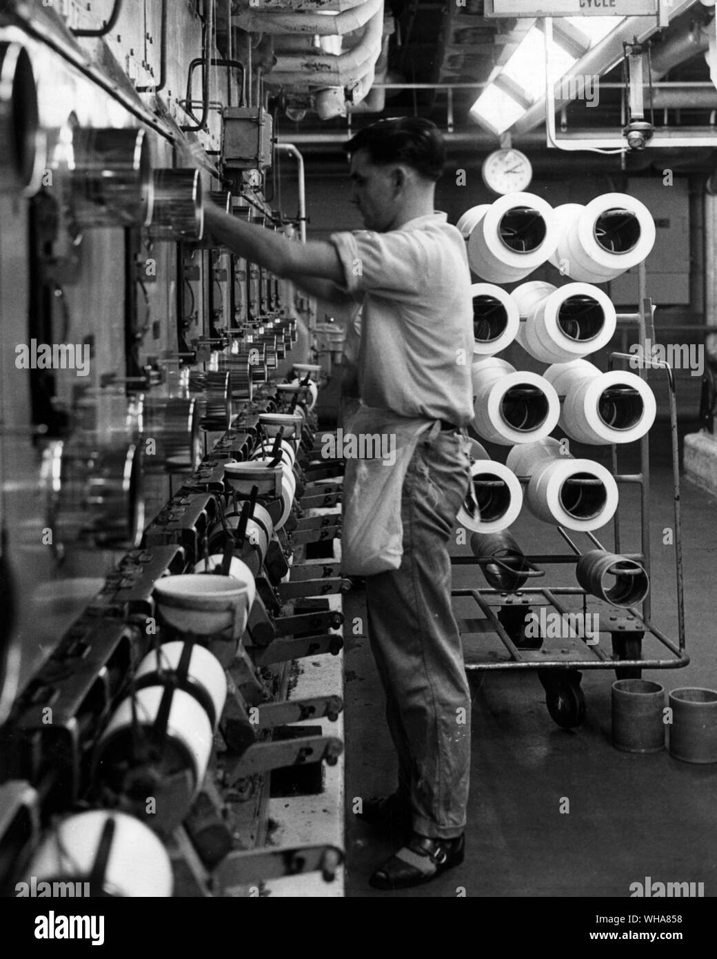 First stage in the production of nylon yarn involves melting the polymer and extruding it through spinnerets. Currents of air cool and solidify the extruded polymer which is then wound onto cylinders ready for cold drawing and subsequent processing. Here some of the spinning units in the main plant at the BNS headquarters at Pontypool Monmouthshire. British Nylon Spinners Ltd Stock Photo
