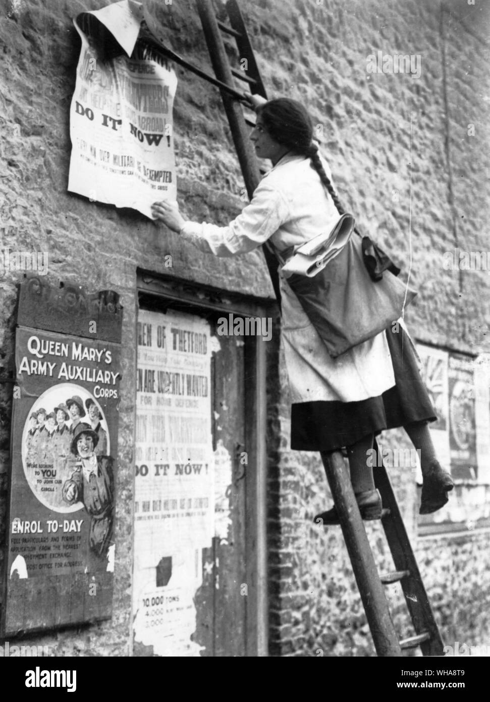 The girl of Thetford who is carrying on her father's appointment of official bill poster and Town Crier at work with her ladder and paste, posting a call to the men of the district Stock Photo