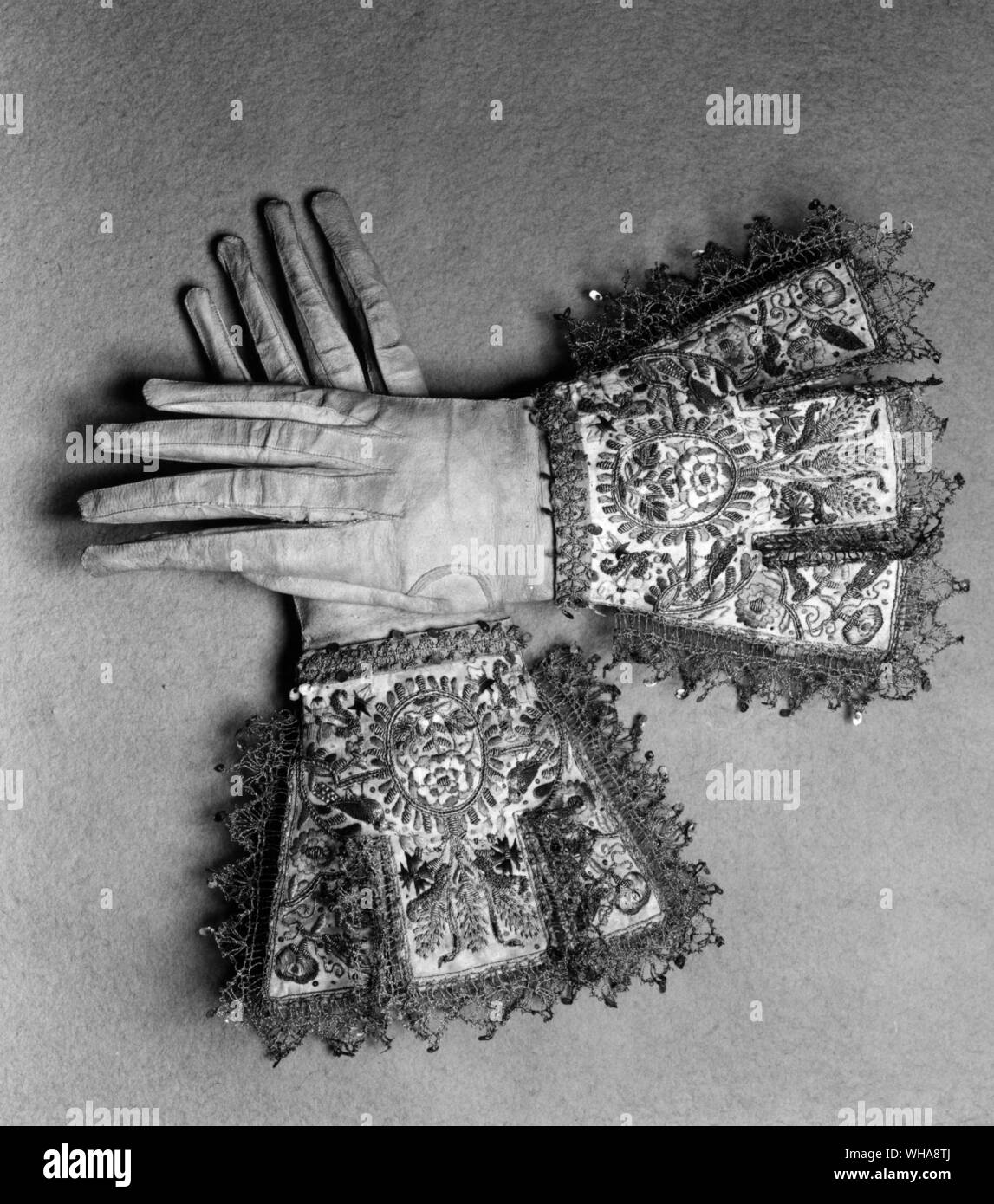 Pair of gloves. leather trimmed with satin and embroidered with silver and silver gilt thread metal ship and coloured silks. Trimmed with gold bobbin lace. c 1700 Stock Photo