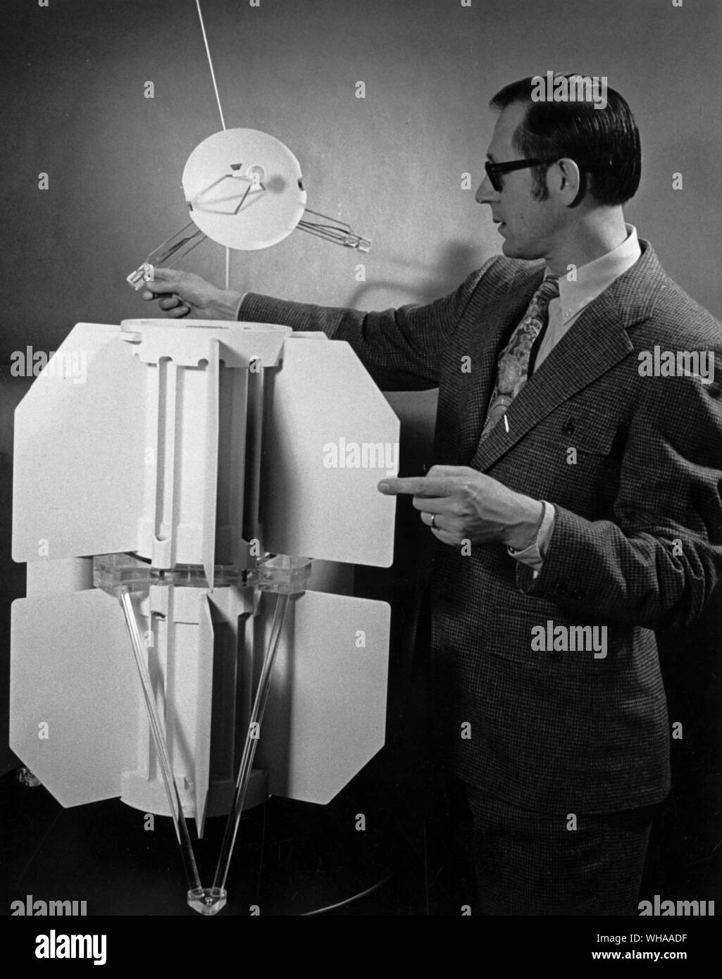 One of the two tandem sets of nuclear generators on a model of NASA's Pioneer spacecraft is being inspected by Bernard J Rock, AEC SNAP-19/ Pioneer radioisotope thermoelectric generator program manager. In the background is a larger model of a set of the AEC developed atomic batteries Stock Photo
