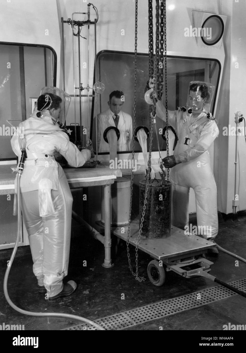 Workers in a specially sealed area at the AERE Harwell wearing an improved pressurised ventilated PVC suit. 7th January 1959 Stock Photo